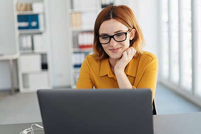 Woman Wearing Glasses While Looking at Her Laptop Computer